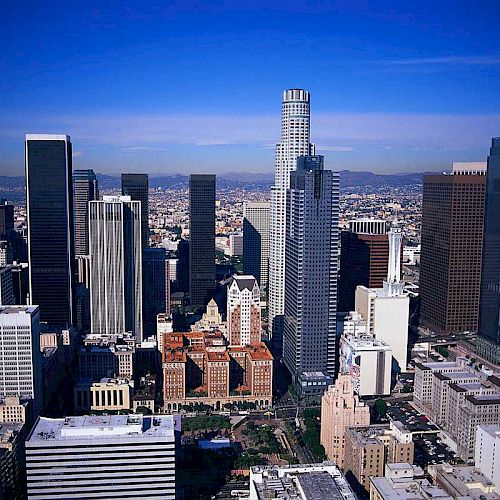 The image showcases a cityscape with numerous skyscrapers and tall buildings against a clear blue sky, likely a major metropolitan area.