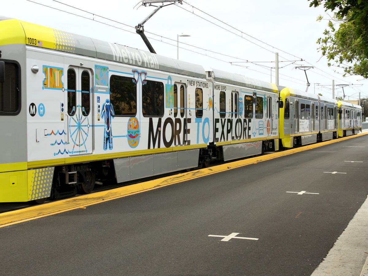 A train with colorful art and the text "MORE TO EXPLORE" on its side is at a train station platform.